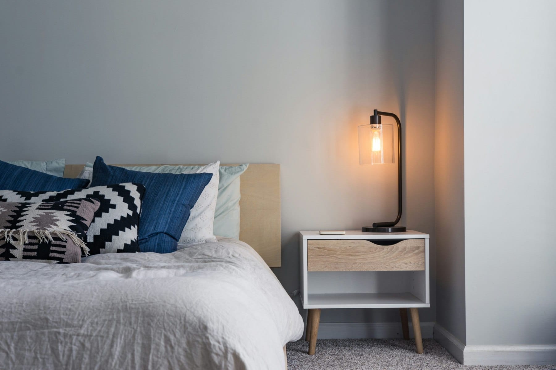 Quarto luminoso com cama e mesa de cabeceira